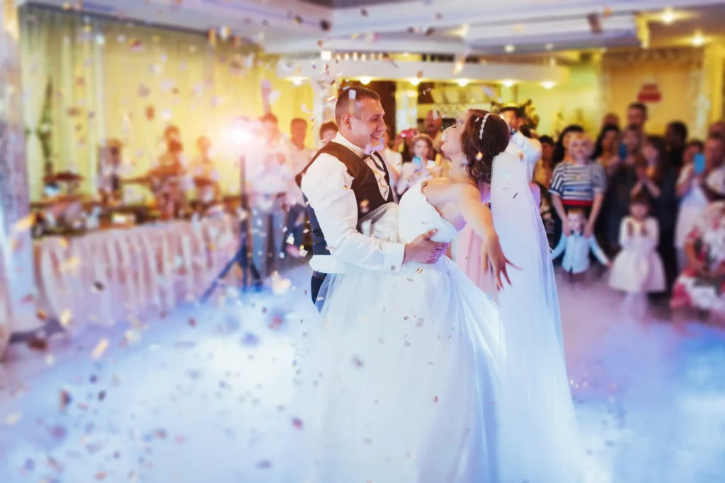 A bride and groom dancing as guests watch at the reception